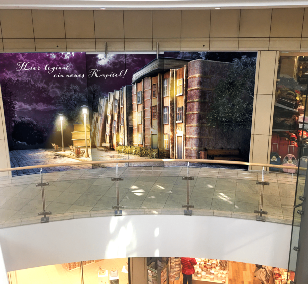 Leerstandsbeklebung im Tibarg Center. Abgebildet sind Häuser aus Büchern mit dem Text "Hier beginnt ein neues Kapitel"